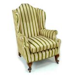 An early 20th century Queen Anne style wing armchair, upholstered in striped dark green and gold