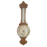 A mid 20th century oak cased aneroid barometer and thermometer, with foliate carved decoration, 24