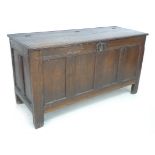 A 17th century oak chest, three plank lift top over a four panel front, later hinges, raised on