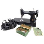 A group of four sewing machines, comprising a vintage Singer Featherweight 221K1 portable electric