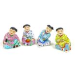 A group of four Chinese figures, late 20th century, each modelled as a seated child, smiling