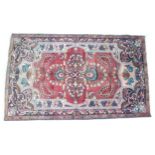 A Lilian rug with red ground, floral design and blue border, 204 by 122cm.