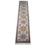An Azarbijan runner with cream ground, multiple medallions set in a row and red border, 300 by 70cm.