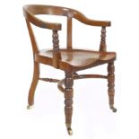 A late victorian oak desk / office chair, with shaped saddle seat, bowed rail supported to the front
