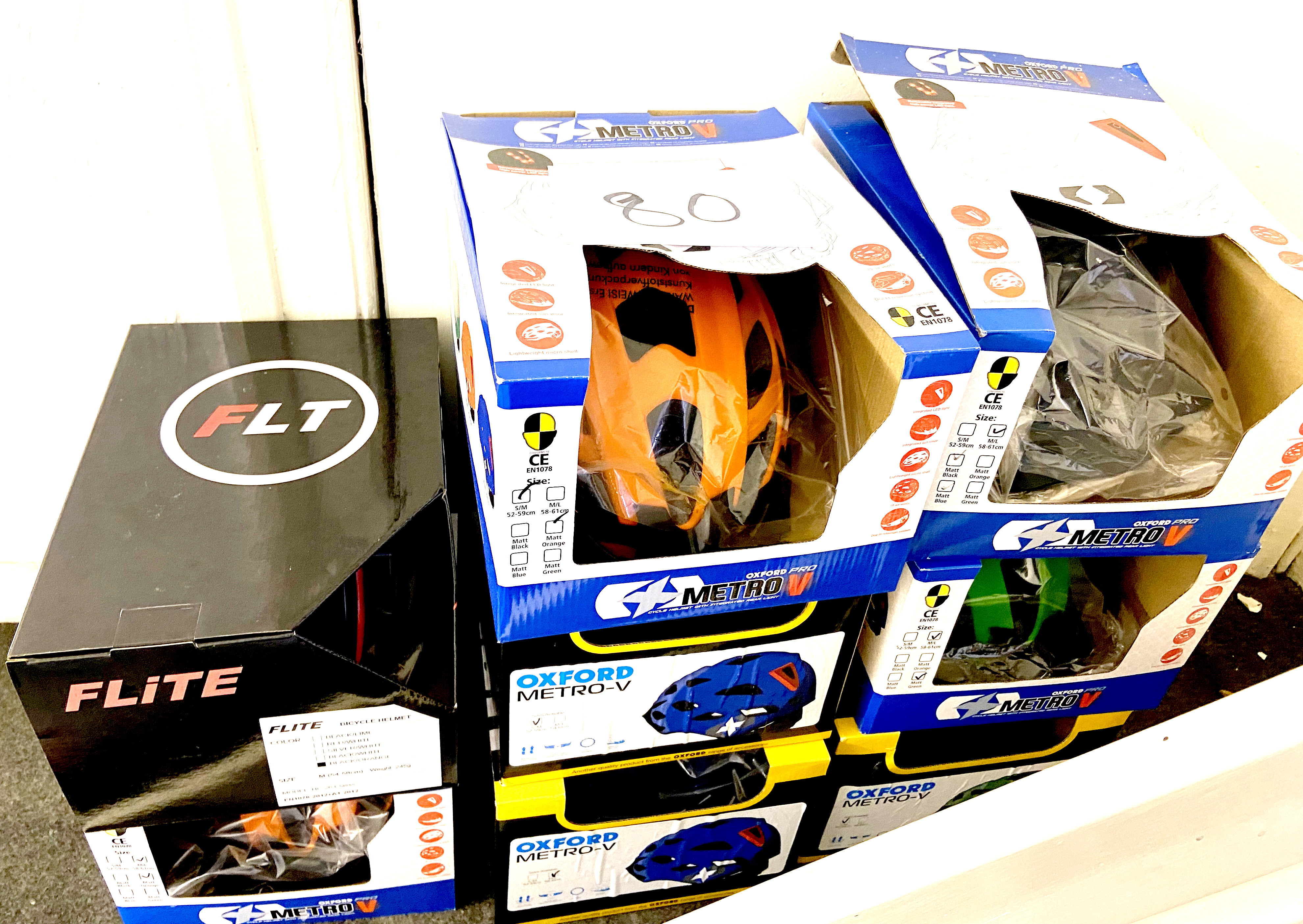 A group of eight boxed bike helmets, comprising seven Oxford Metro-V, and a Flite HC-26 Classic,