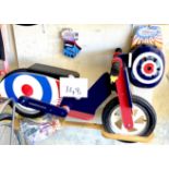 A KiddiMoto children's wooden balance bike, in the form of a blue and red 'Mod Brit' moped, together