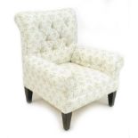 An Edwardian child's armchair, with croll over arms, upholstered in buttoned pale cream floral