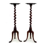 A mirrored pair of mahogany candle stands, with small circular surfaces supported on barley twist