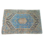 A large rug with blue ground, beige central hexagonal lozenge encased in a dark blue bracket design,