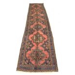 A Karajeh runner with red ground, seven medallions set in a row, with blue and cream borders, 383 by