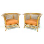 A pair of modern bamboo armchairs, with caned sides and curved back, separate seat cushion in tan/
