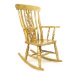 A Windsor style beech rocking chair, mid 20th century, with pierced splat and slatted back, shaped