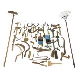 A group of vintage hand tools, including a hoe, a rake, hammers, shears, sickles, hand drill, and