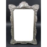 An ERII silver framed mirror on stand, with elaborate foliate and scroll decorative border design,