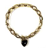 A 9ct gold fancy link bracelet with red stone heart charm, each link hallmarked, 15.6g.