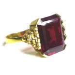 A Middle Eastern gold and imitation ruby dress ring, the emerald cut red stone, 40 by 20 by 5mm,