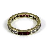 A 9ct white gold, ruby and paste eternity ring, the scroll engraved band set with twelve round cut