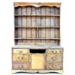 An early 20th century country made pine dresser, with plate rack above its base which features seven