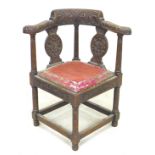 A Victorian oak corner chair, with heavily carved frame, drop in seat, raised on turned supports