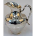 A Mexican Sterling silver jug, of baluster form with a scrolling handle, raised on a circular foot,