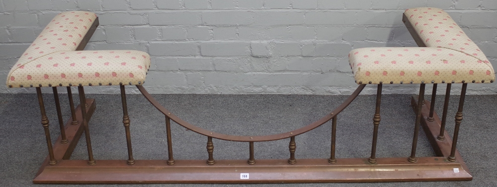 An early 20th century brass and cream upholstered club fender with sloped curb,