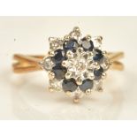 A gold, diamond and sapphire cluster ring, mounted with a circular cut diamond to the centre,