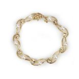 A gold and cultured pearl bracelet, in a pierced and engraved serpentine link design,