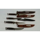 Four early 20th century steel bladed knives, with leather sheaths, including examples by Marble's U.