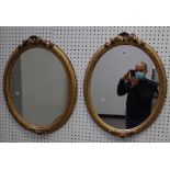 A pair of gilt framed oval wall mirrors with floral chased frames, 55cm wide x 61cm high, (2).