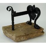 A black painted cast iron boot scraper on paw feet mounted on a rectangular stone slab,