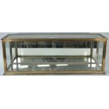 A brass table top rectangular display cabinet with mirrored base and back, 83cm wide x 30cm high.