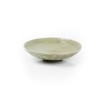 A Chinese celadon dish, Ming dynasty, the underside moulded with lappets beneath a dark green glaze,