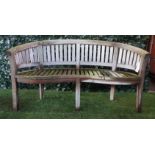 A teak framed semi-elliptic garden bench with slatted back and seat, on block supports,