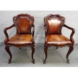 A pair of Victorian mahogany framed brown leather upholstered open armchairs,