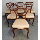 A set of six Victorian rosewood balloon back dining chairs with carved waist rail and serpentine