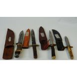 Two early 20th century bone handled hunting knives and two daggers, with leather sheaths,