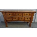 A Chinese elm side cabinet with seven frieze drawers flanked by shaped sides on block supports,