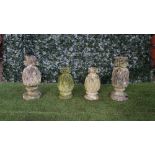 Two graduated pairs of reconstituted stone pineapple finials on turned socles,