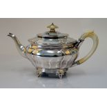 A silver teapot, of panelled oval form, raised on three feet,