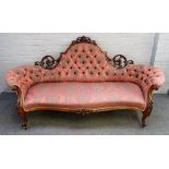 A Victorian carved and pierced walnut framed tub back sofa, with serpentine seat on scroll supports,