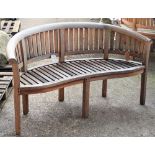 A teak framed semi-elliptic garden bench with slatted back and seat on block supports,