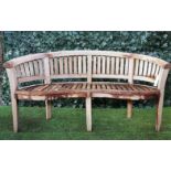 A teak framed semi-elliptic garden bench with slatted back and seat, on block supports,