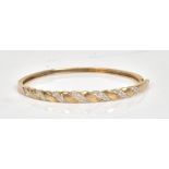 A 9ct gold and diamond set oval hinged bangle, mounted with circular cut diamonds,