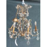 A 20th century gilt metal and glass six light chandelier, with scrolling branches and faceted drops,