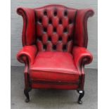 A red leather upholstered George I style wingback armchair on cabriole supports,
