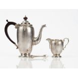 A silver coffee pot of oval form, raised on a circular foot, with brown composition fittings,