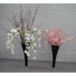 A pair of modern tall black glass tapered vases containing artificial tiger orchids and blossom,