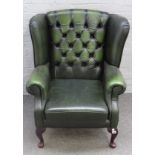 A green leather upholstered George I style wingback armchair on cabriole supports,