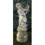 A reconstituted stone figure group of a cherub riding a serpent, on a circular baluster base,