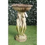 A reconstituted stone bird bath, the fluted reservoir on a pedestal relief cast as the three Graces,